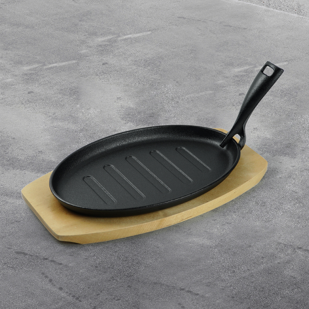 The cast-iron steak plate and oval-shaped frying pan with a wooden base are suitable for kitchens and dining rooms